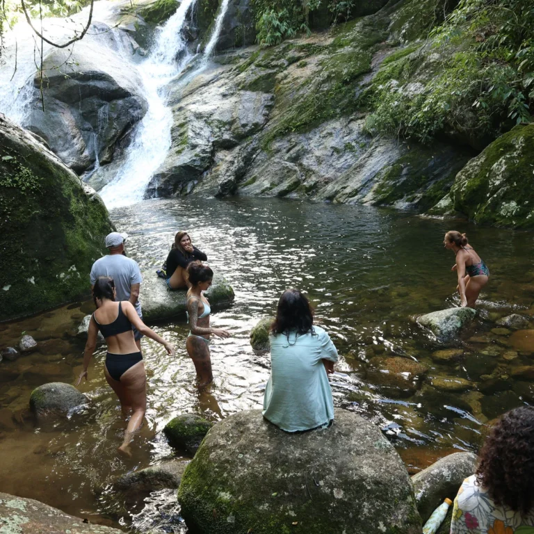 Grupo em banho de cachoeira durante retiro na Mata Atlântica