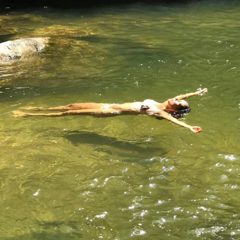 Pessoa boiando de braços abertos em piscina natural na Mata Atlântica