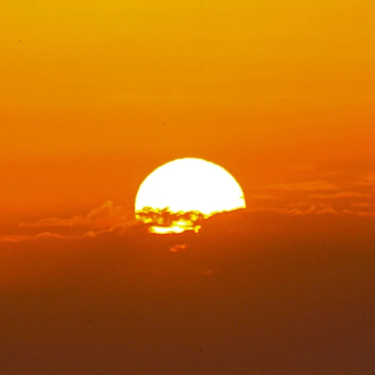 Pôr do sol alaranjado visto da Flor de Maria, na serra do RJ