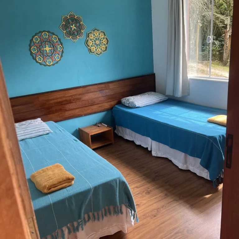 Quarto azul com duas camas na hospedagem da Flor de Maria